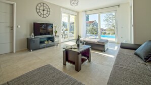 A modern living room with a TV, sofa, and a dining area. - Brand new 2019 villa with pool, barbecue, WiFi, bicycles, dishwasher, washing machine (Tinjan)
