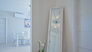 A room with a large mirror, a potted orchid, and a dining area with white chairs and a table. - Brand new 2019 villa with pool, barbecue, WiFi, bicycles, dishwasher, washing machine (Tinjan)