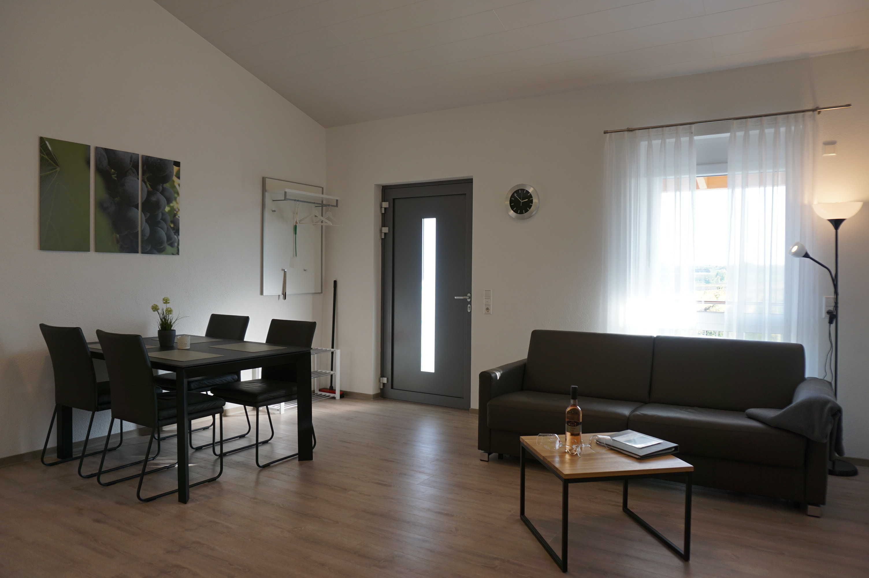 A modern living room with a dining area, a sofa, a coffee table, and a lamp.