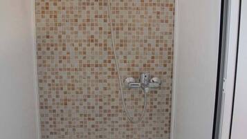 Een douche met betegelde wand en een handdouche.