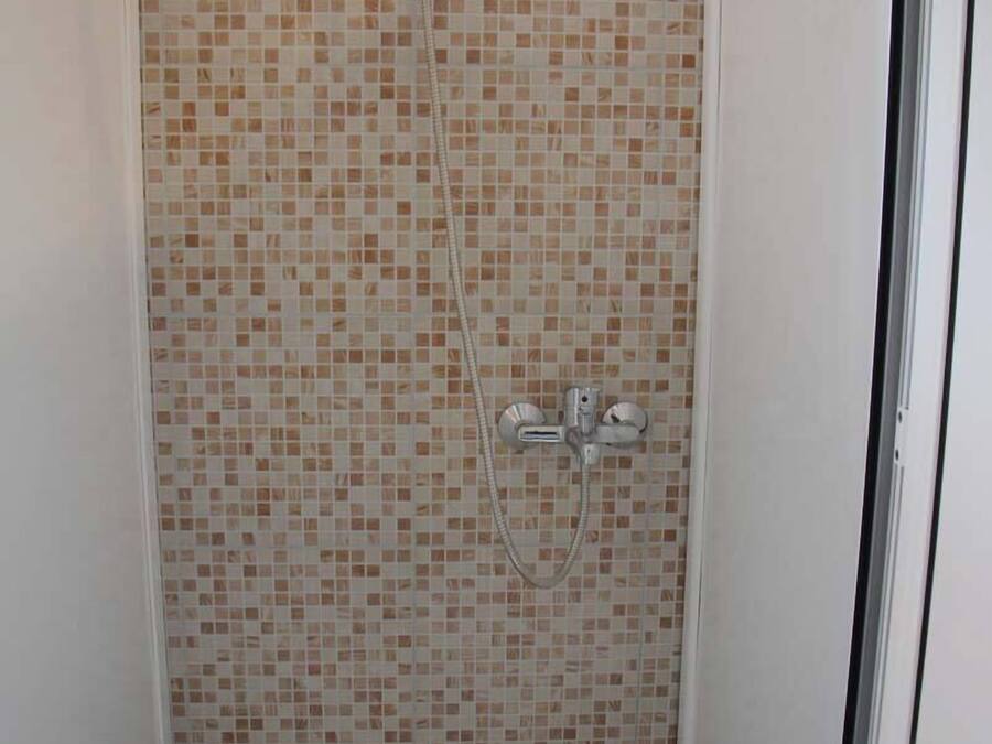 Een douche met betegelde wand en een handdouche.