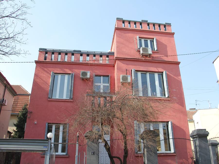Un bâtiment rouge doté de nombreuses fenêtres et de plusieurs unités de climatisation.