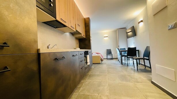 A modern kitchen with stainless steel appliances, wooden cabinets, and a dining area with a table and chairs. - Villa Linda - ONE-BEDROOM APARTMENT sleeps 5 (Bardonecchia)