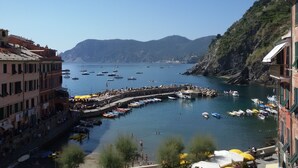 A coastal town with a marina filled with boats, a promenade with people, and buildings along the waterfront.