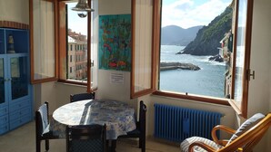 A room with a view of the sea, a table with chairs, a radiator, and a blue cabinet.