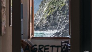 A window with a view of a rocky coastline and ocean.