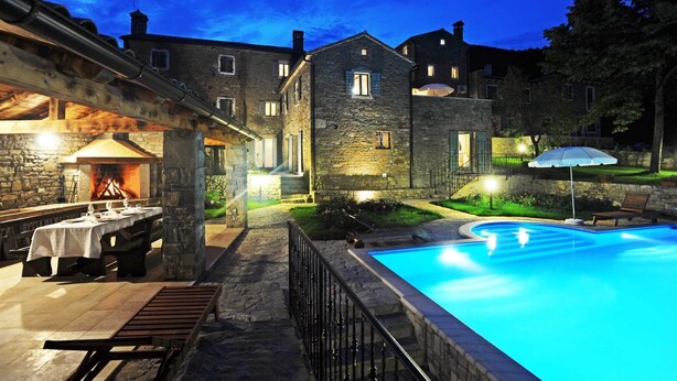 Un bâtiment en pierre doté d’une piscine, d’un espace extérieur aménagé et d’une cheminée.