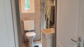 A compact bathroom with a toilet, sink, and glass shower enclosure.