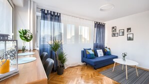Uma sala de estar moderna com um sofá azul, piso de madeira e uma pequena mesa branca.
