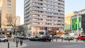 Um hotel alto com um anúncio da Coca-Cola no topo, vários andares e uma área de estacionamento na frente.