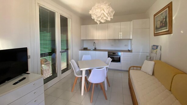 A compact living space with a kitchenette, a dining area, a sofa, and a TV on a dresser. - Maristella, a few steps from the center and the beach (Marina di Campo)
