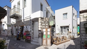A white building with a balcony and a stone wall. - L'anima suites (Skiathos)