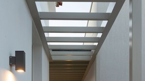 A corridor with a wooden floor, white walls, and a glass ceiling. - L'anima suites (Skiathos)