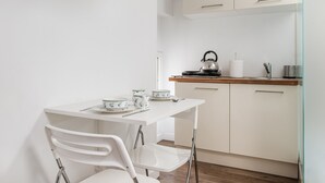 Une cuisine moderne avec des meubles blancs, un plan de travail en bois et une bouilloire.