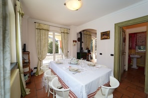 Comedor con una mesa lista para cuatro, sillas blancas y una ventana con cortinas.