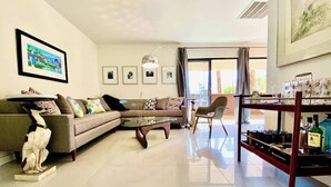 A modern living room with a sofa, armchair, coffee table, and a bookshelf. - Mod Downtown Escape, Pool, Spa, Tennis, Pickleball (Palm Springs)