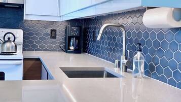 A modern kitchen with a stainless steel sink, a coffee maker, and a water dispenser.