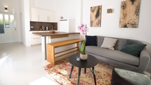 Ein modernes Wohnzimmer mit einem grauen Sofa, einer Holzbank und einem kleinen runden Tisch mit einem Blumentopf.