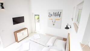 Ein modernes Schlafzimmer mit Bett, Fernseher, Schreibtisch und Bildern an den Wänden.