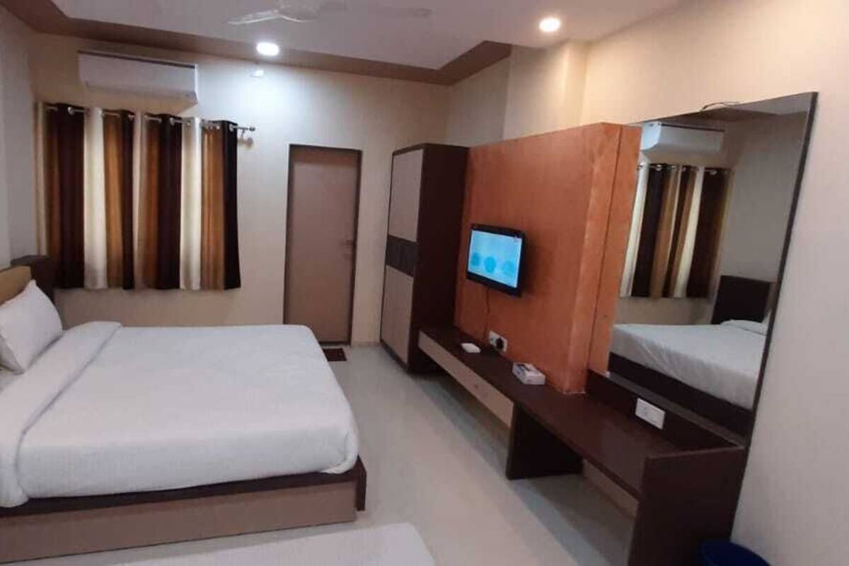 A hotel room with a bed, a TV, a mirror, and a wardrobe.