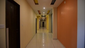Um corredor com piso ladrilhado, uma porta com a inscrição '101' e um corredor com teto com iluminação embutida e um desenho geométrico.