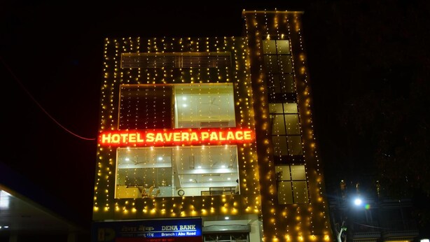 Um edifício com uma placa que diz "HOTEL SAVERA PALACE" e uma placa de banco visível do DENA BANK.