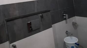 Een badkamer met een wit toilet, een douche en een bidet.