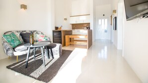 A modern living room with a sofa, a small round table, and a kitchen area in the background.