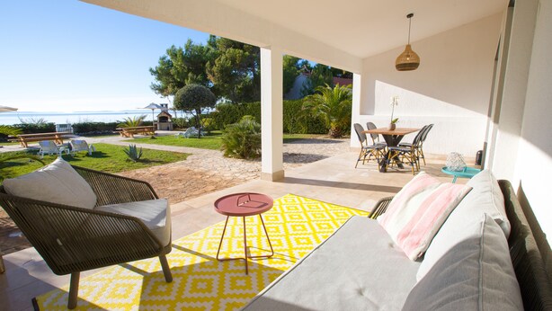 A covered outdoor seating area with a sofa, chairs, and a table.