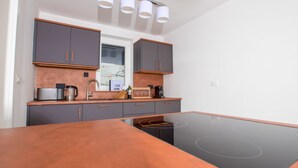 Una cucina moderna con mobili grigi, un piano cottura a induzione nero e un ripiano in legno.