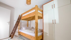 Un letto a castello con struttura in legno, una porta bianca e un armadio con ante in vetro.