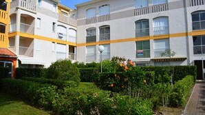A multi-story residential building with balconies, a well-maintained garden, and a clear sky. - Air-conditioned apartment. Close to shops and sea. Parking. Rated Atout France 1*. (Argelès-sur-Mer)