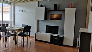 A modern kitchen with a TV, built-in oven, and a dining area with chairs and a table. - Air-conditioned apartment. Close to shops and sea. Parking. Rated Atout France 1*. (Argelès-sur-Mer)