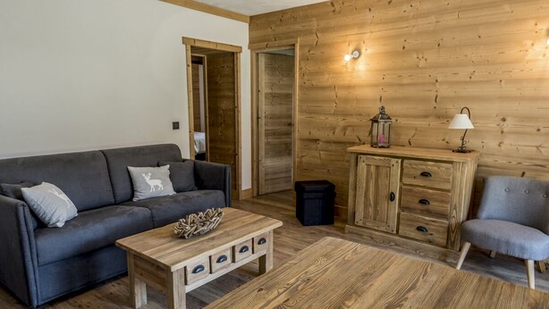 A cozy living room with a grey sofa, a wooden coffee table, a cabinet, and a chair. - New apartment in the center of the village and 150 meters from the ski bus. (Samoëns)