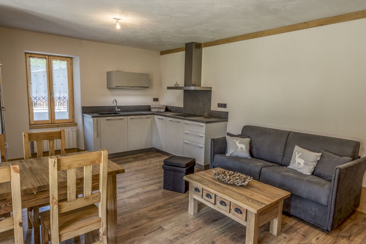 Un espacio habitable compacto con kitchenette, comedor y zona de estar con sofá y mesa de centro.