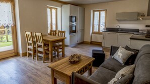 A cozy living room with a sofa, a wooden coffee table, and a dining area with chairs and a table. - New apartment in the center of the village and 150 meters from the ski bus. (Samoëns)
