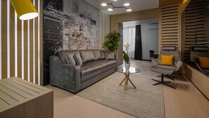 Un salon moderne avec un canapé gris, une table basse en verre et une suspension jaune.