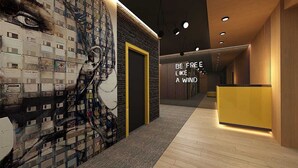 Un intérieur moderne avec un mur décoré d’une fresque en briques, un comptoir d’accueil et un couloir doté d’un plancher en bois.