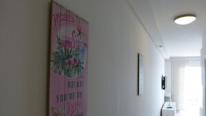 A hallway with a pink wall art featuring a flamingo, palm leaves, and the text "Relax! You're on Beach Time." - Apartment NoStress (Omis)