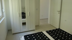 A bedroom with a wardrobe, a bed with a star-patterned bedspread, and a door leading to another room. - Apartment NoStress (Omis)