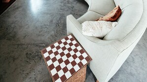 Ein großzügiger Wohnbereich mit einem gebogenen, weißen Sofa, einem karierten Couchtisch und einer Küche im Hintergrund.