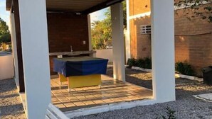 A covered outdoor seating area with a bench and a table, surrounded by gravel and a small plant. - Pousada Vale do Gravatá (Gravata)