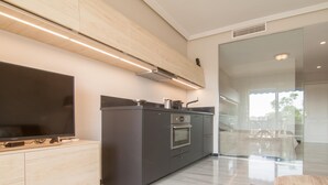 A modern kitchen with a flat-screen TV, built-in oven, and a large island.