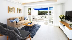 A modern living room with a sofa, coffee table, and a TV. - Apartment in Playas del Duque for 4 people| Casa Granada 232 (Puerto Banús - Marbella)