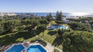 A resort with multiple swimming pools, lush greenery, and a view of the sea. - Apartment in Playas del Duque for 4 people| Casa Granada 232 (Puerto Banús - Marbella)