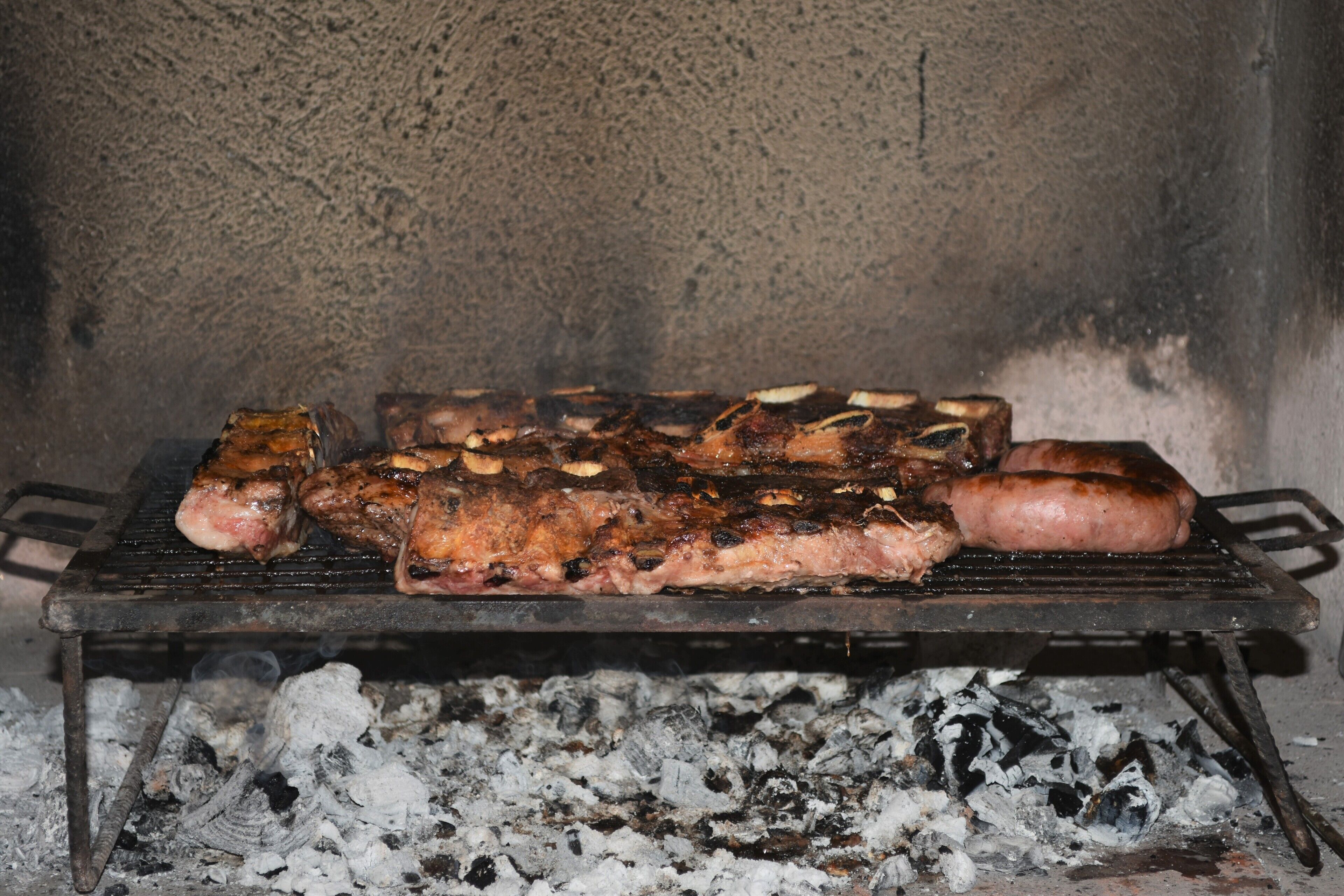 A grill with various meats cooking over charcoal.