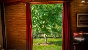A cozy room with a bed, a television, and a window with curtains. - Hotel de campo granja el aromo (Nono)