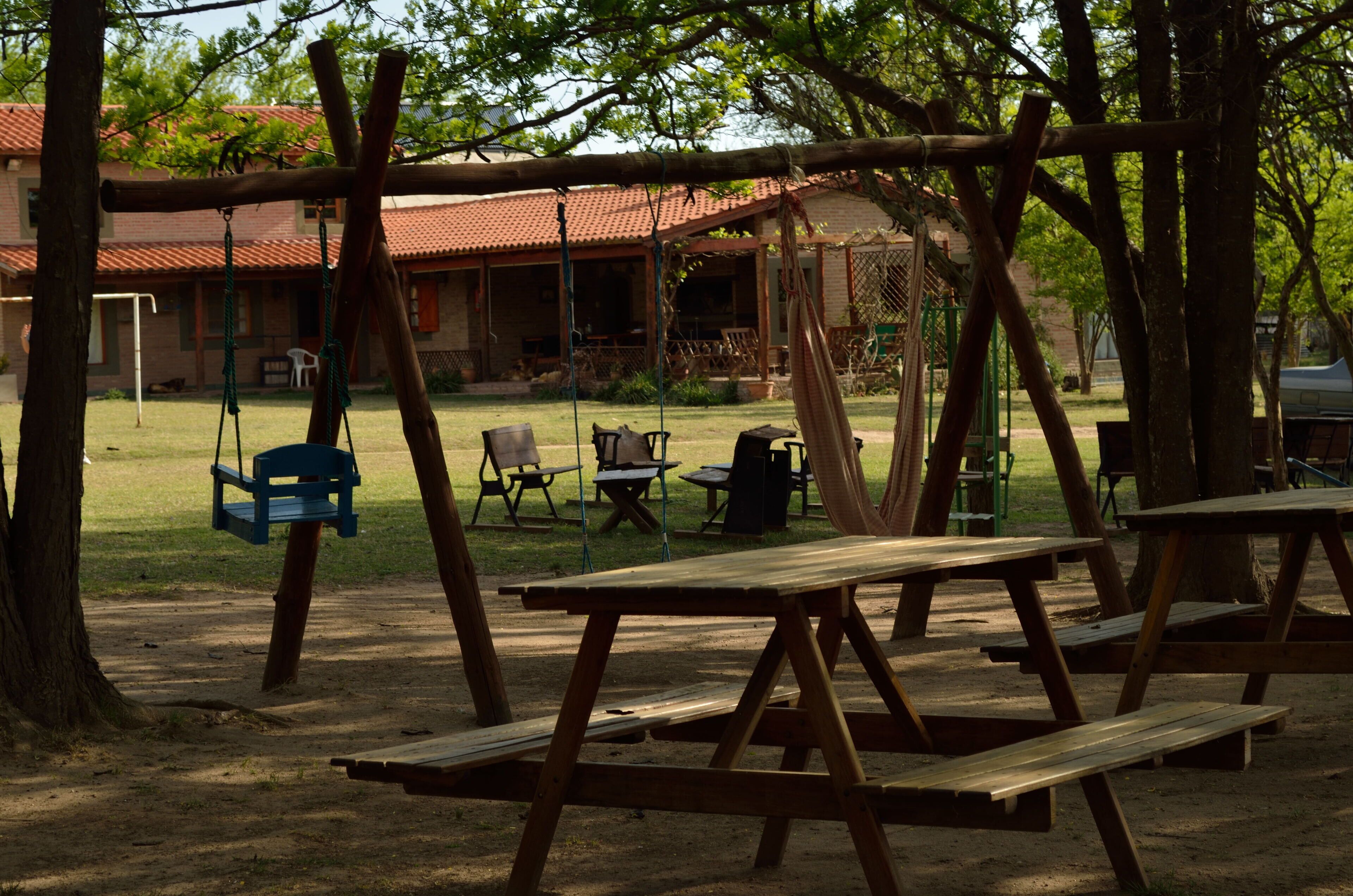 A picnic area with wooden benches and a swing set.