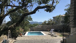 Un área de piscina con pared de piedra, una hamaca y una silla.