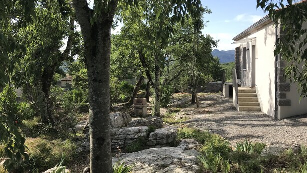 Un edificio rústico de piedra con un banco de madera y una escalera que conduce a la entrada.